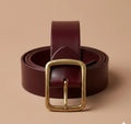 Brown leather belt with a gold buckle on a beige background