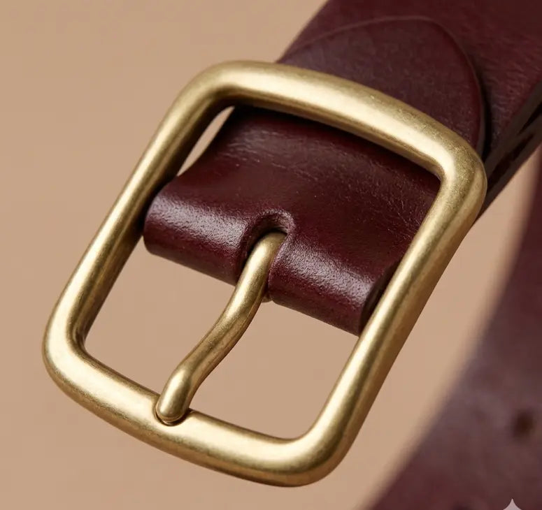 Close-up of a brown leather belt with a gold buckle on a beige background