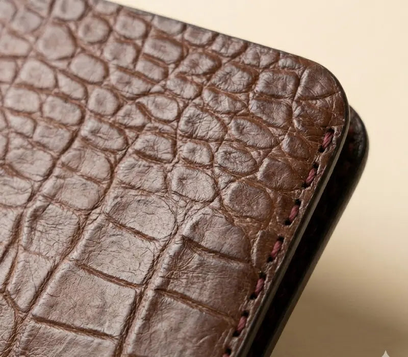 Close-up of a brown leather phone case with crocodile texture.