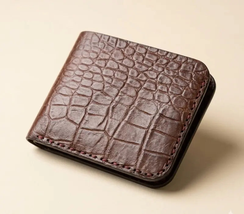 Brown leather wallet with crocodile texture on a beige background