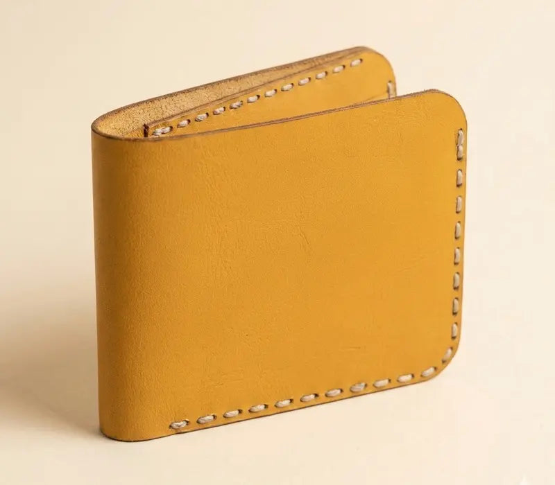 Yellow leather wallet with decorative stitching on a beige background