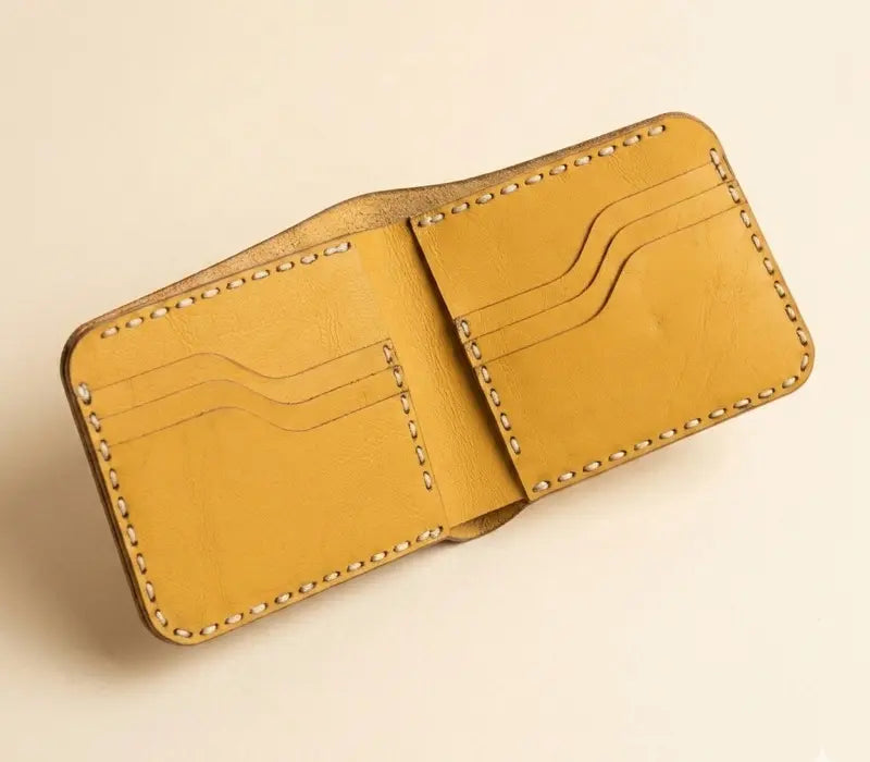 Yellow leather wallet with stitching details on a beige background