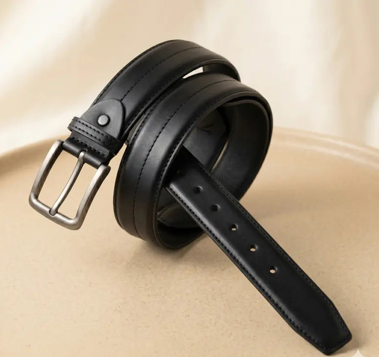 Black leather belt with a silver buckle on a beige background