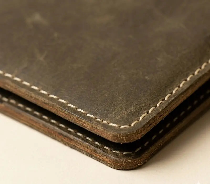 Close-up of a brown leather wallet with visible stitching on a light background