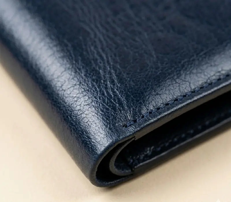 Close-up of a blue leather wallet on a beige surface