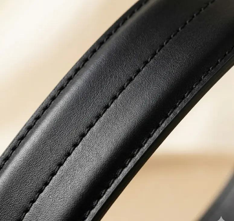 Close-up of a black leather belt with visible stitching on a beige background