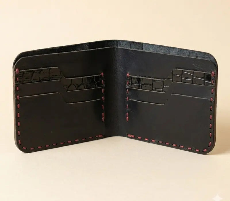 Black leather wallet with red stitching on a beige background