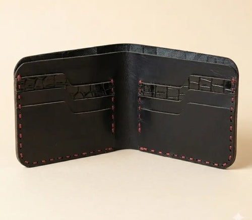 Black leather wallet with red stitching on a beige background
