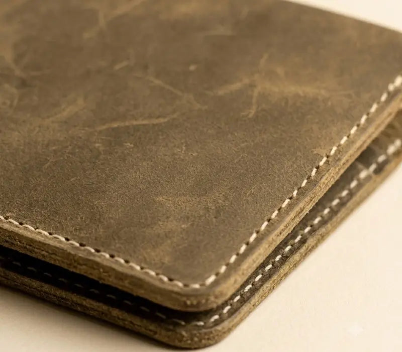 Close-up of a brown leather wallet with visible stitching on a light background