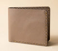 Brown leather wallet with gold stitching on a beige background