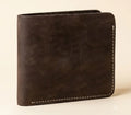 Brown leather wallet with white stitching on a beige background