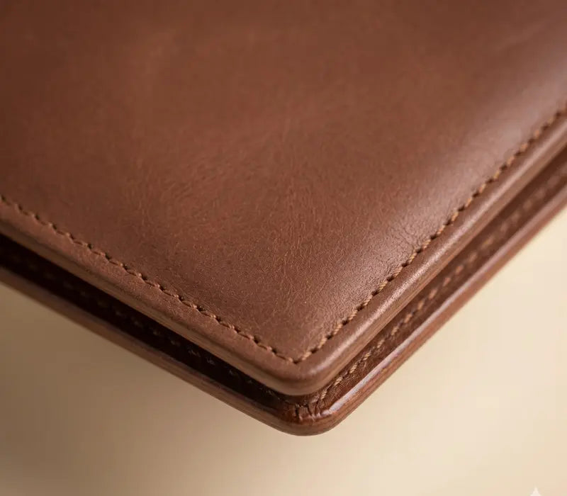 Close-up of a brown leather wallet corner on a light beige background