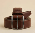 Brown leather belt with silver buckle on a beige background