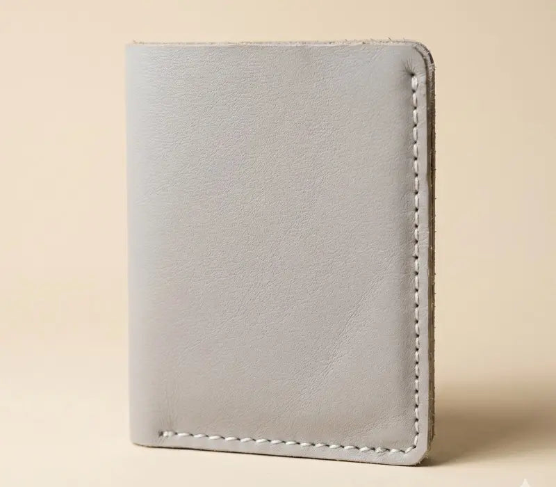 Light gray leather wallet with white stitching on a beige background