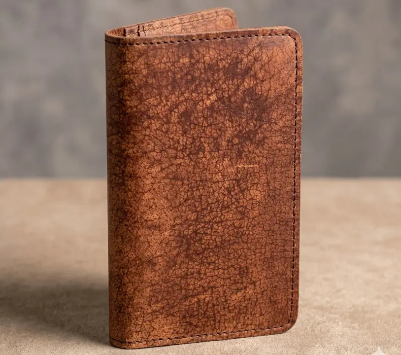 Brown leather wallet on a textured surface with a blurred background