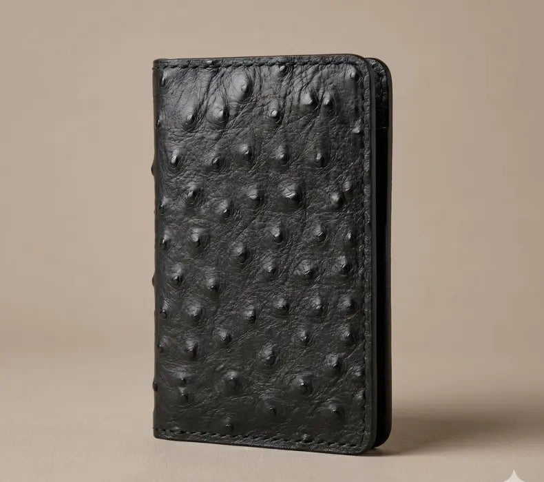 Black genuine ostrich leather handmade long wallet with brass snap closures on a beige background
