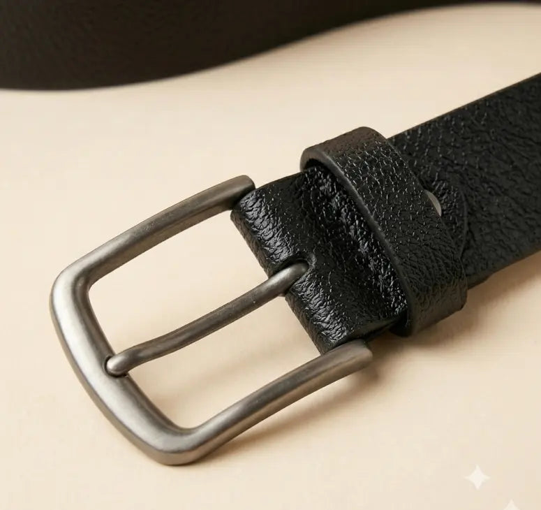 Close-up of a black leather belt with a silver buckle on a beige background