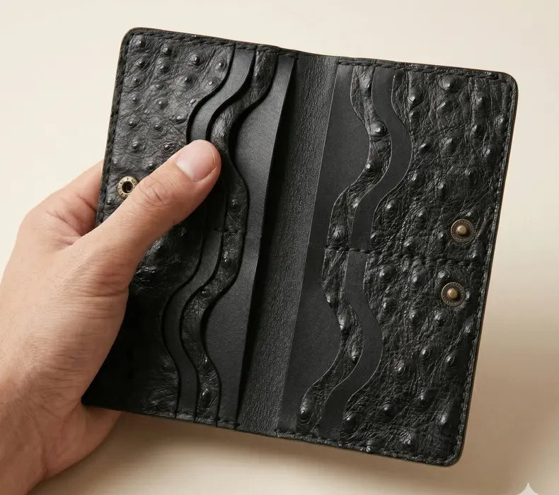 Hand holding a black textured leather wallet against a beige background