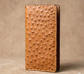 Tan genuine ostrich leather handmade long wallet with wavy card pockets on a beige background