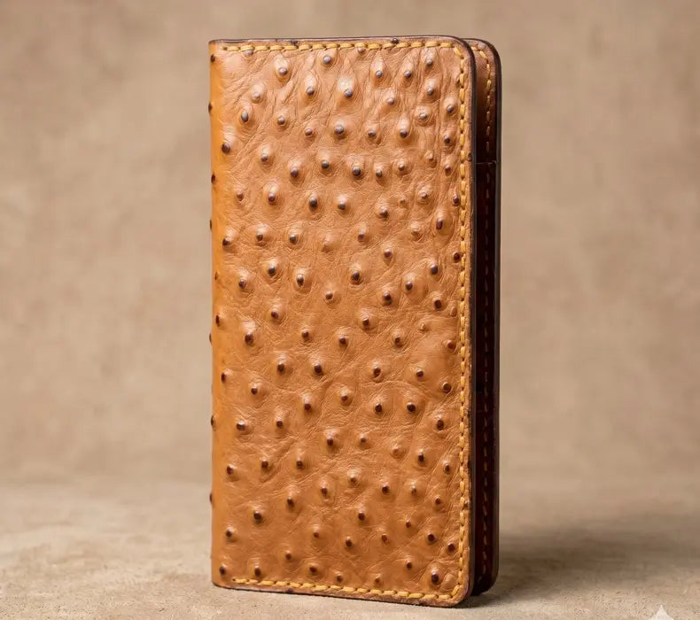 Tan genuine ostrich leather handmade long wallet with wavy card pockets on a beige background