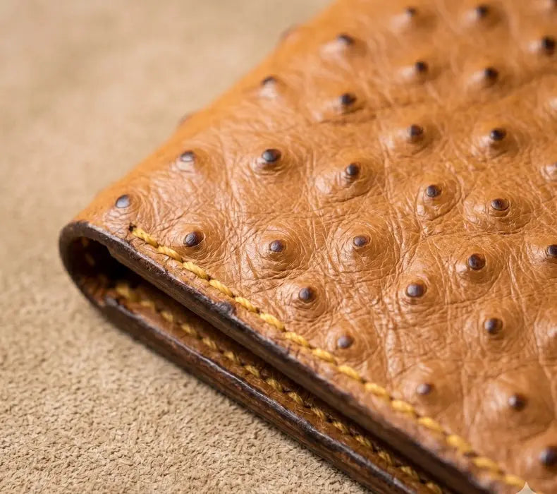 Close-up of a brown leather wallet with a textured surface on a beige background
