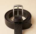 Brown leather belt with a silver buckle on a beige background
