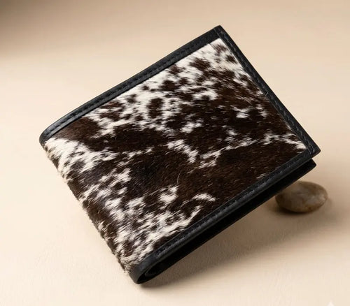Brown and white cowhide wallet on a beige background