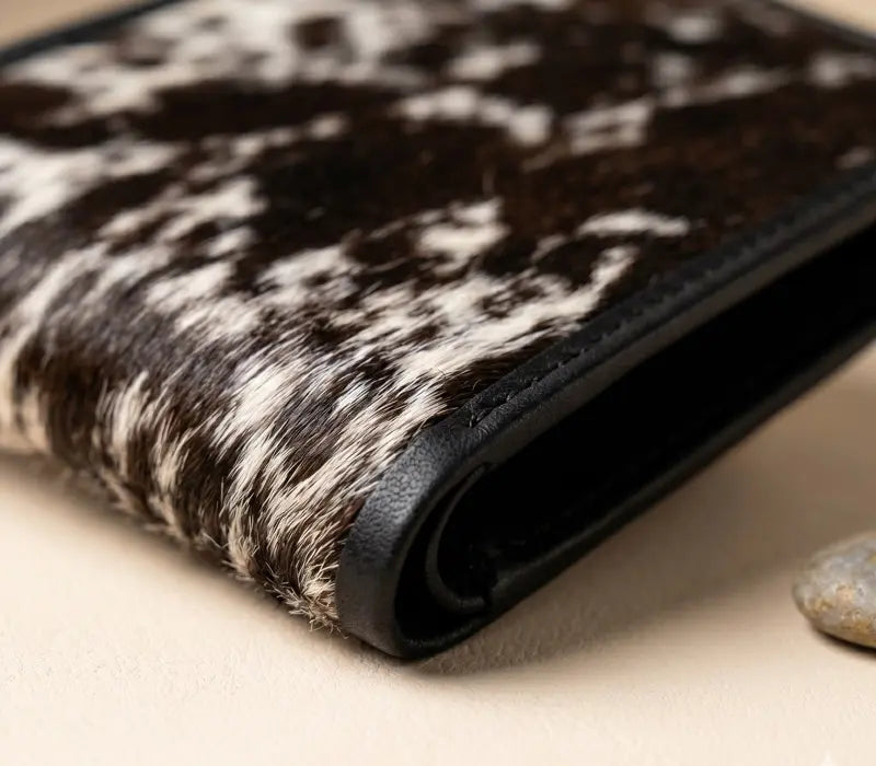 Close-up of a wallet with a cowhide pattern on a beige surface