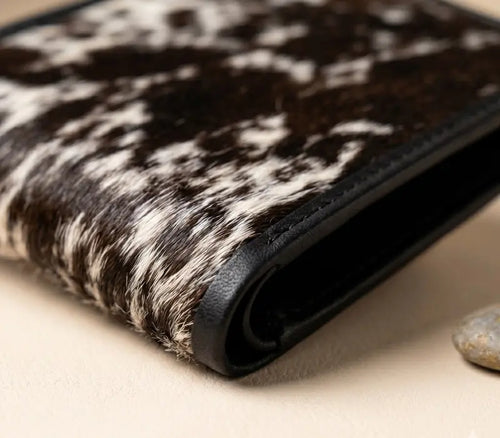 Close-up of a wallet with a cowhide pattern on a beige surface