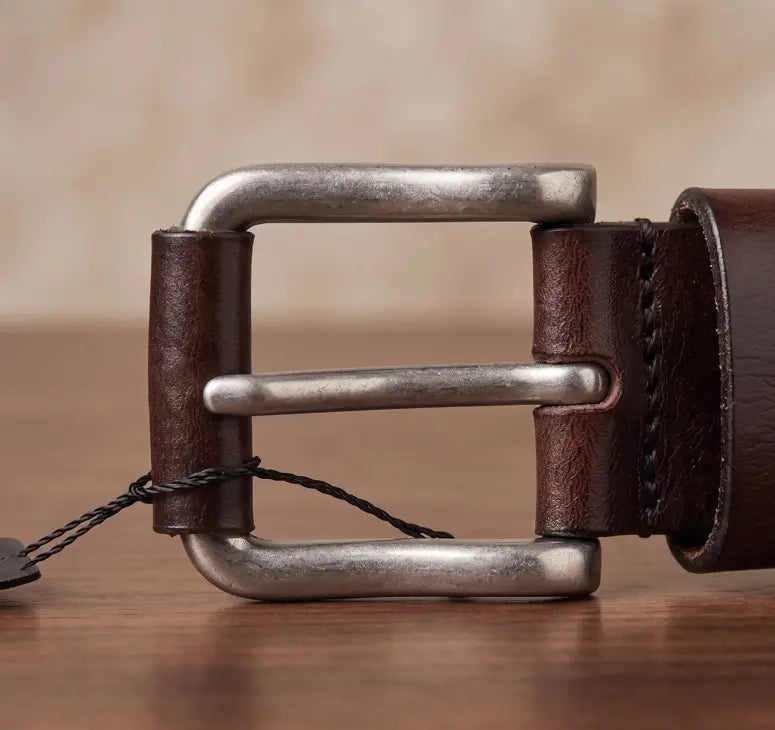Brown leather belt with a silver buckle on a wooden surface