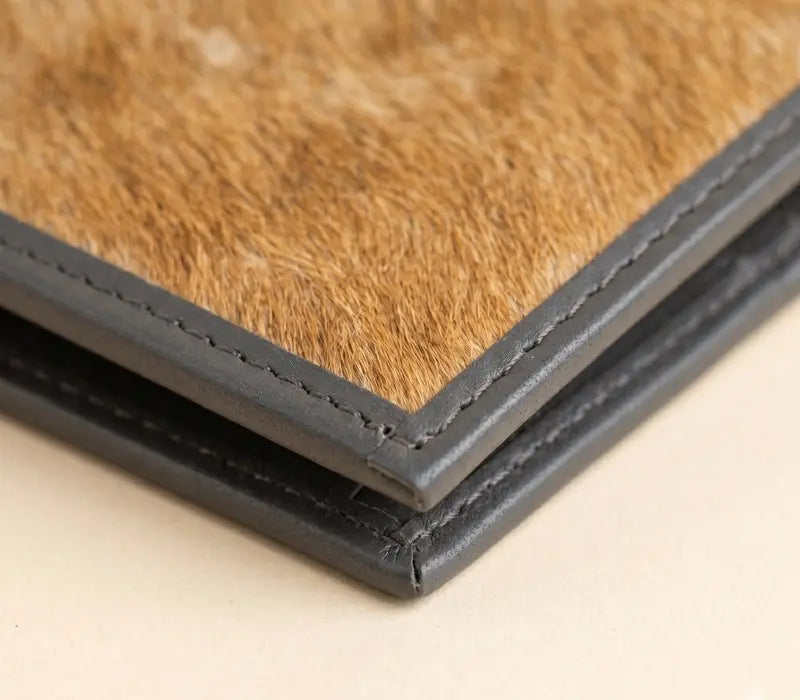 Close-up of a leather-bound book with brown leather cover and black binding.
