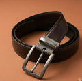 Brown leather belt with silver buckle on a brown background