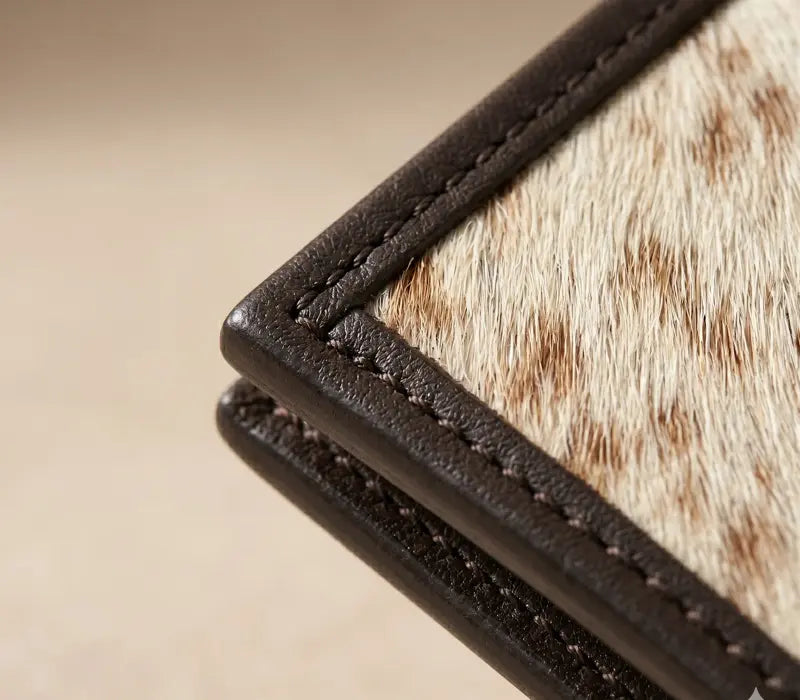 Close-up of a leather-bound book with cowhide cover on a beige background