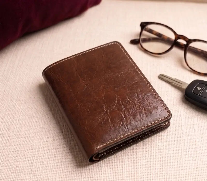 Dark brown full-grain handmade leather card holder with card slots on a beige background