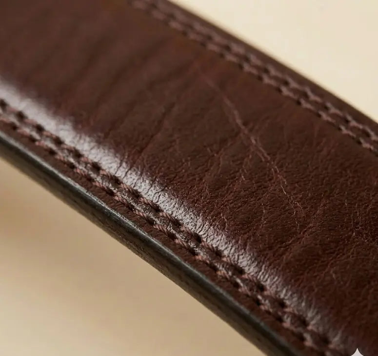 Brown leather belt with a silver buckle on a beige background