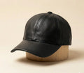 Black full-grain handmade leather peaked cap on a beige background