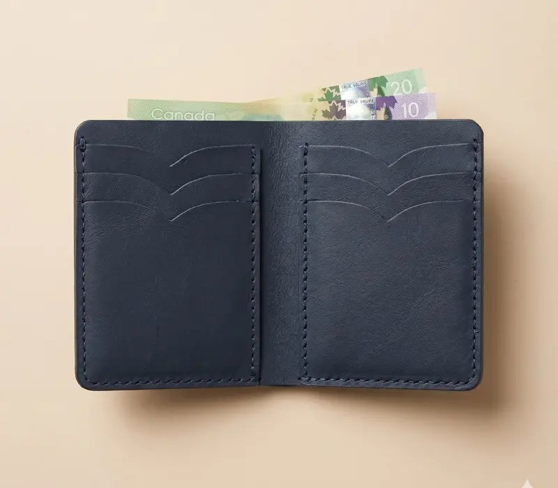 Black leather wallet with Canadian money sticking out on a beige background