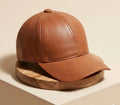 Brown leather cap on a wooden stand with a beige background