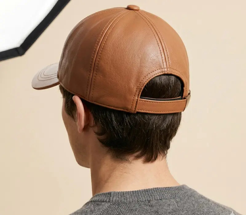 Person wearing a brown leather cap from behind on a beige background