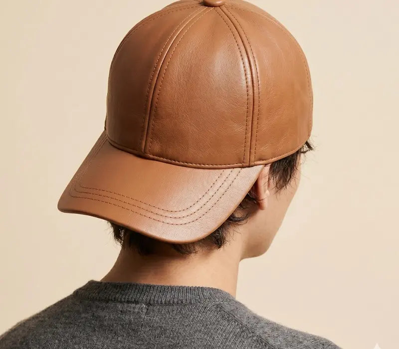 Brown leather cap worn by a person on a beige background