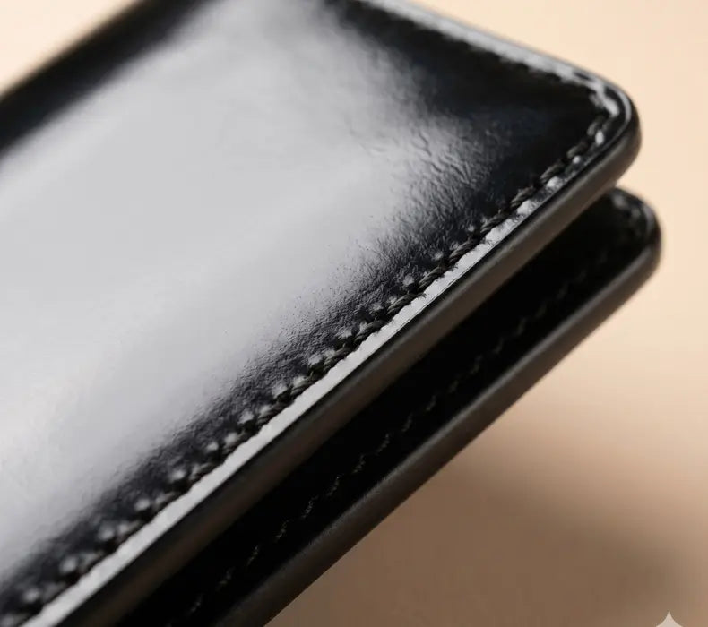 Close-up of a black leather wallet with visible stitching on a beige background