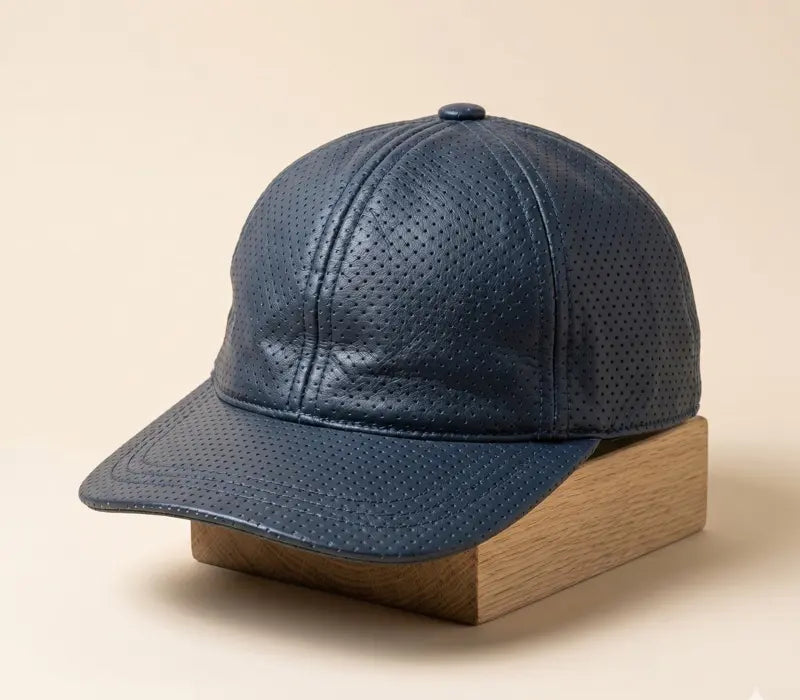 Blue perforated leather cap on a wooden block against a beige background