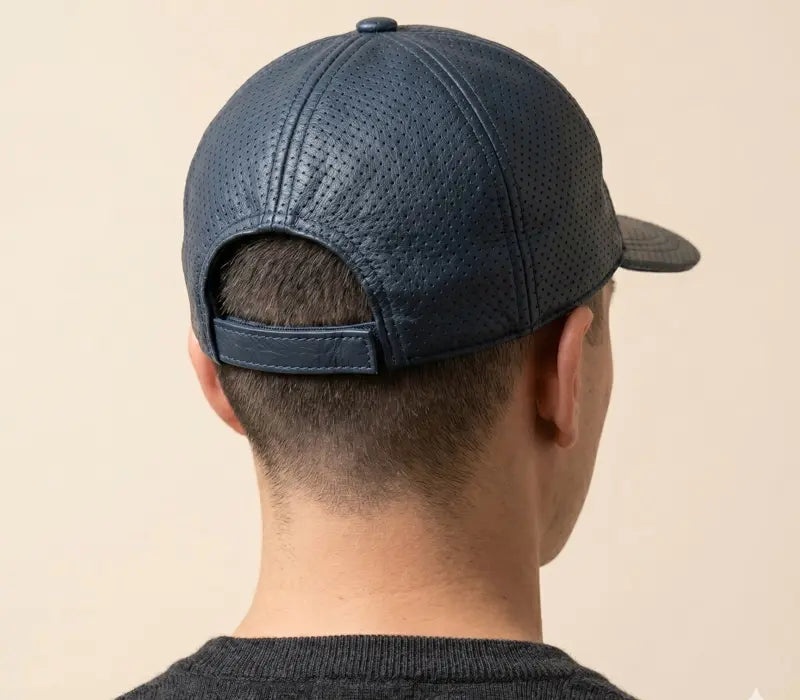 Person wearing a blue textured baseball cap on a beige background