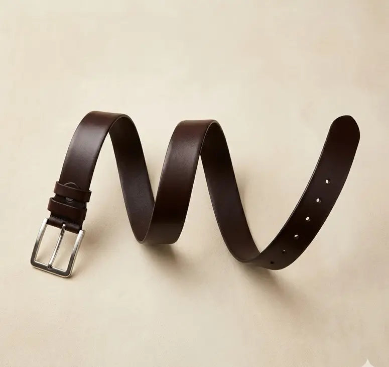 Brown leather belt with a silver buckle on a beige background