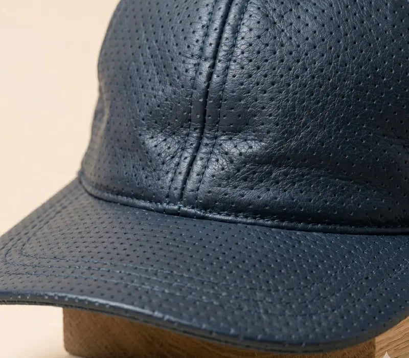 Close-up of a blue leather cap on a beige background