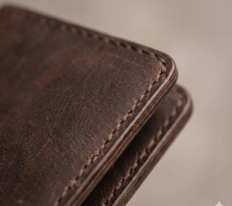 Close-up of a brown leather wallet with visible stitching on a neutral background