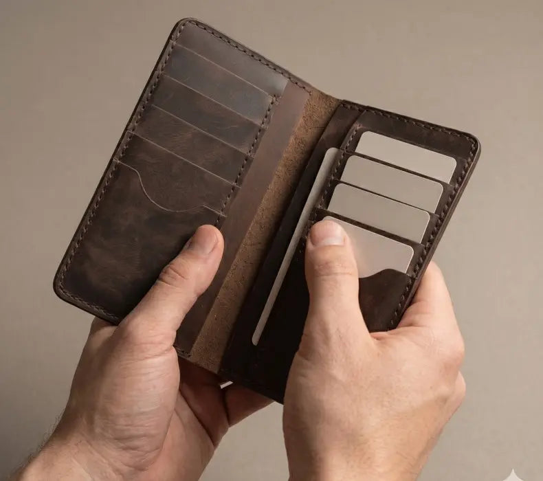 Brown leather wallet held open by a hand against a neutral background