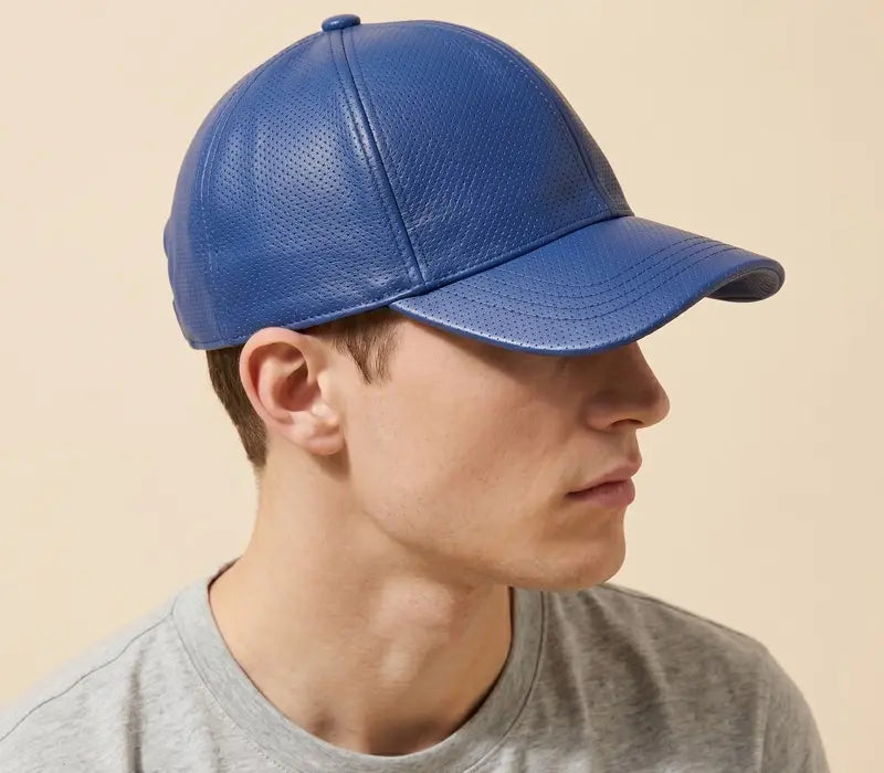 Person wearing a blue textured baseball cap on a beige background