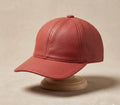 Red textured baseball cap on a beige stand against a beige background