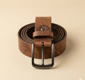 Brown leather belt with a black buckle on a beige background